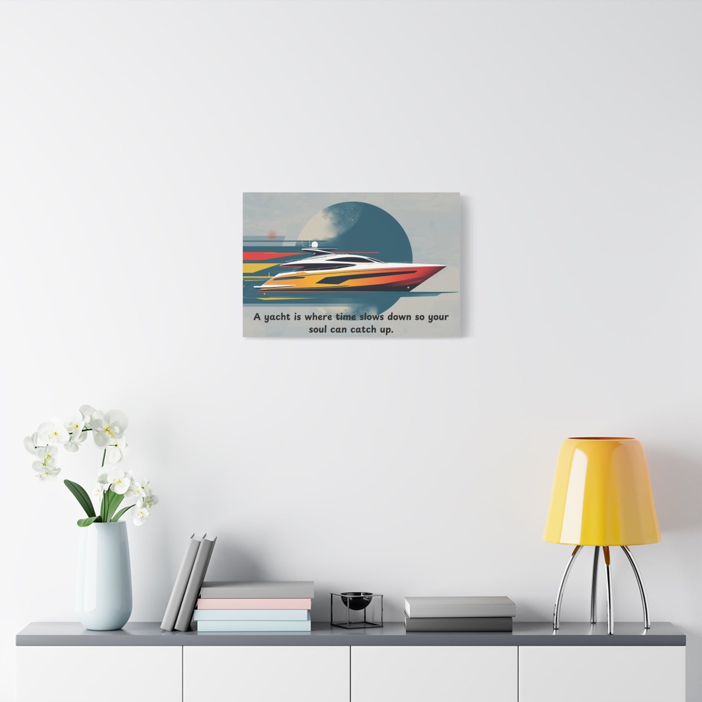 Decorative wall art canvas of a yacht on a white wall above a shelf with books and a lamp.