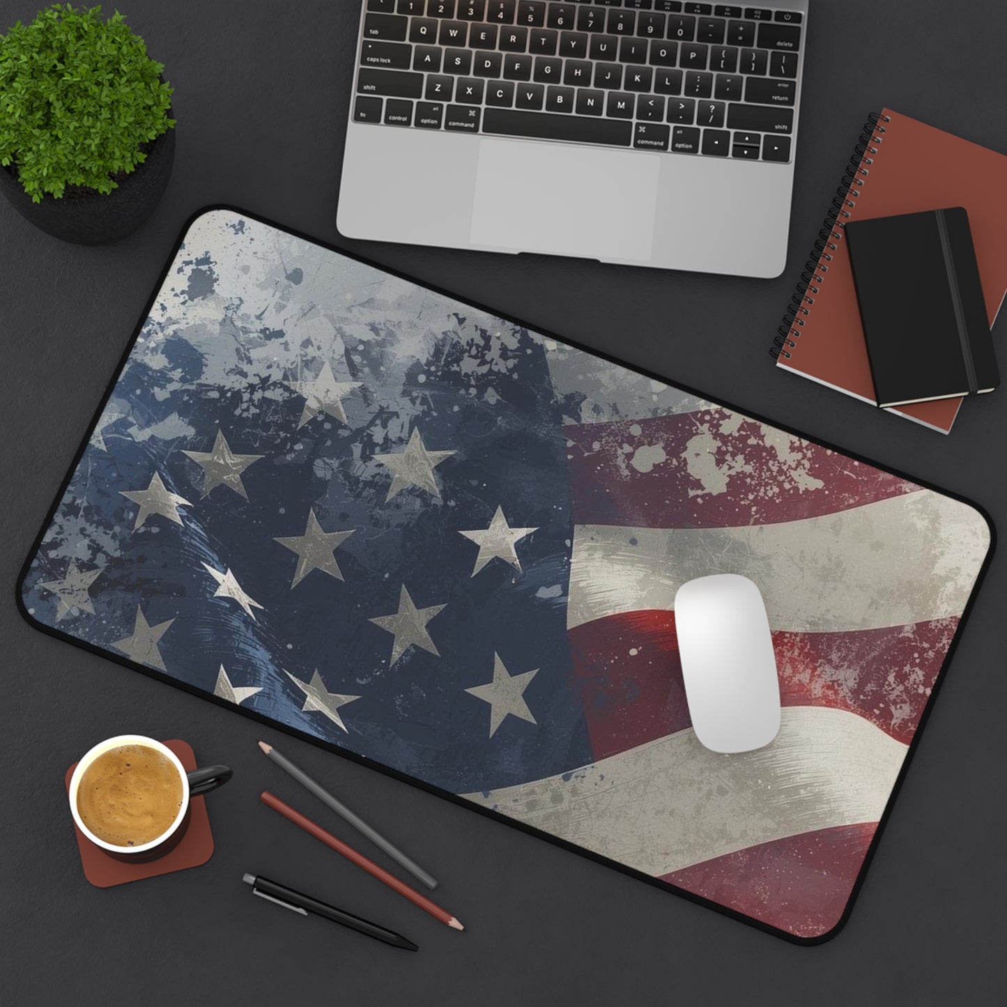 Desk setup with an American flag mouse pad, laptop, notebook, and coffee cup.