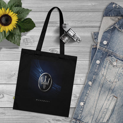 Black tote bag with Maserati logo on a wooden surface with denim jacket and sunflower.