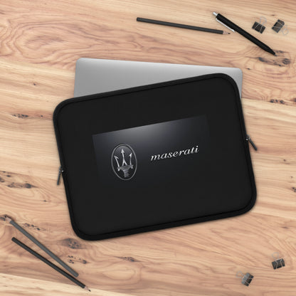 Black Maserati laptop sleeve on a wooden surface with pens and a pencil.