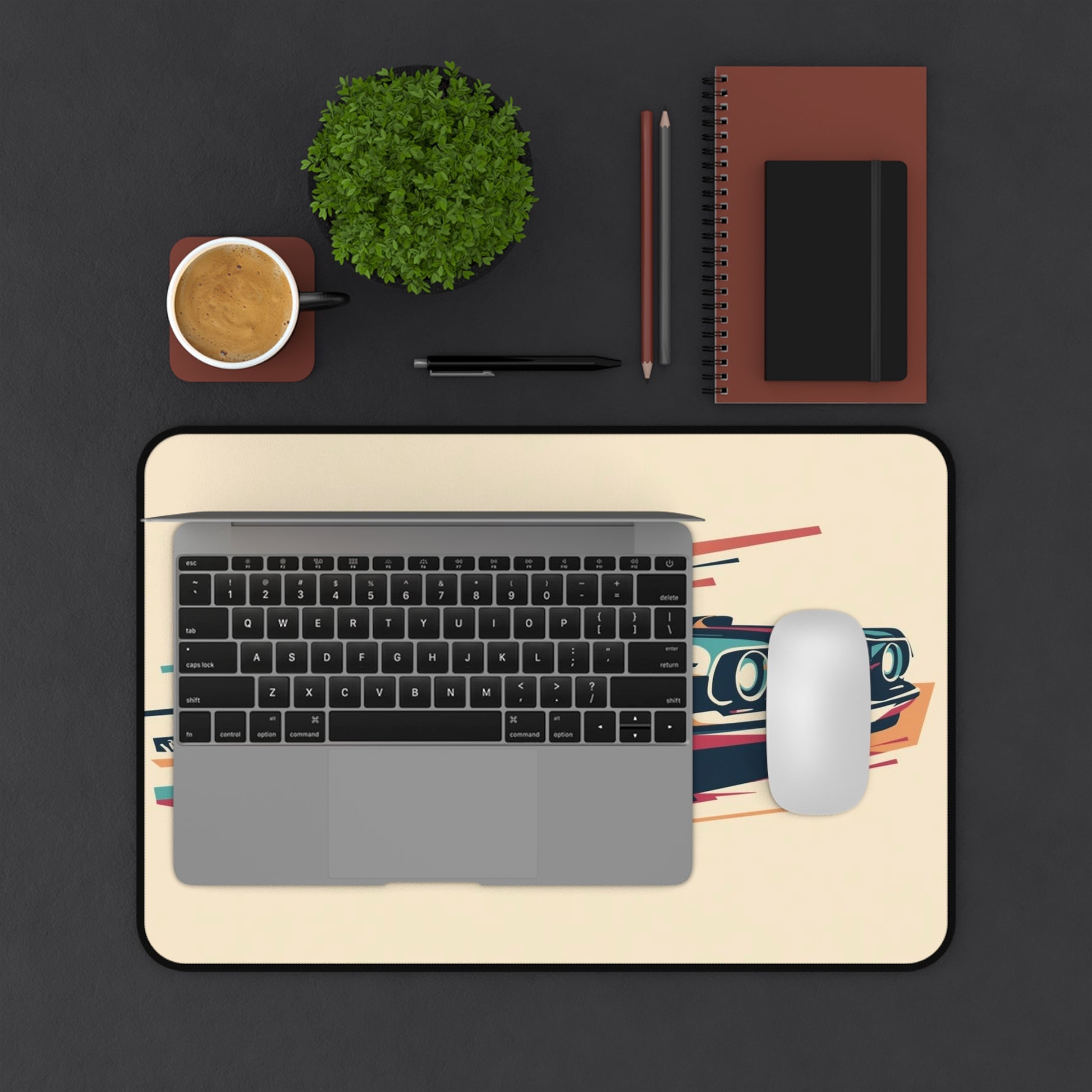 Laptop on a desk with a mouse, notebook, pen, plant, and a mouse pad.