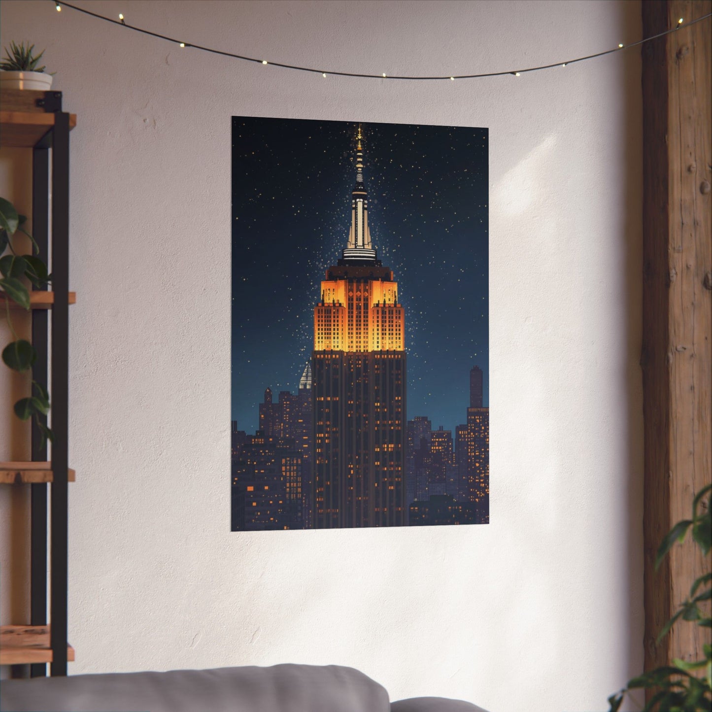 Poster of the Empire State Building on a wall in a room with a plant and shelf.