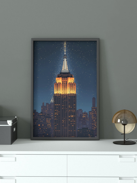 Framed artwork of the Empire State Building on a wall above a white cabinet.