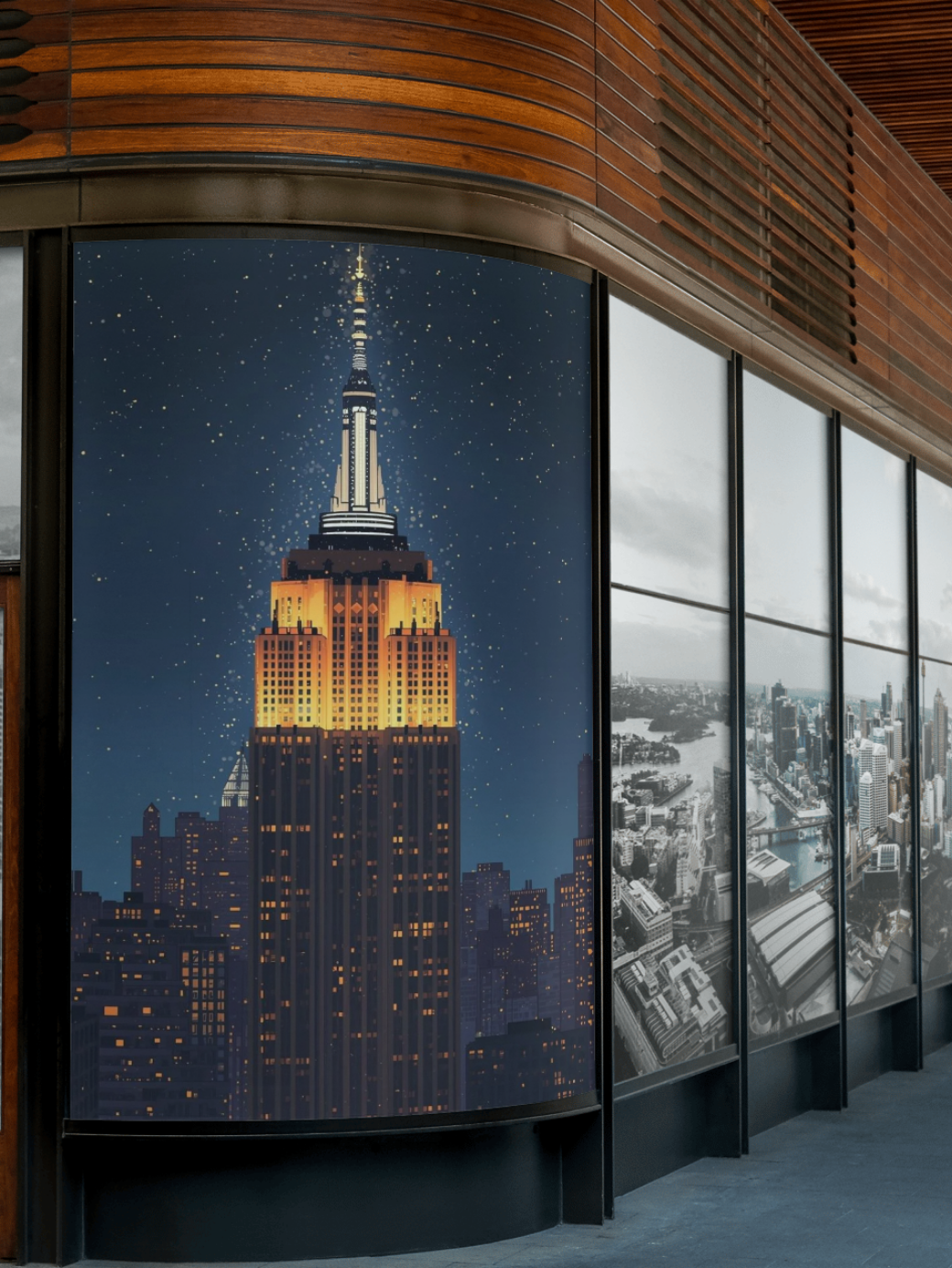 Cityscape with a prominent skyscraper at night, framed by large windows.