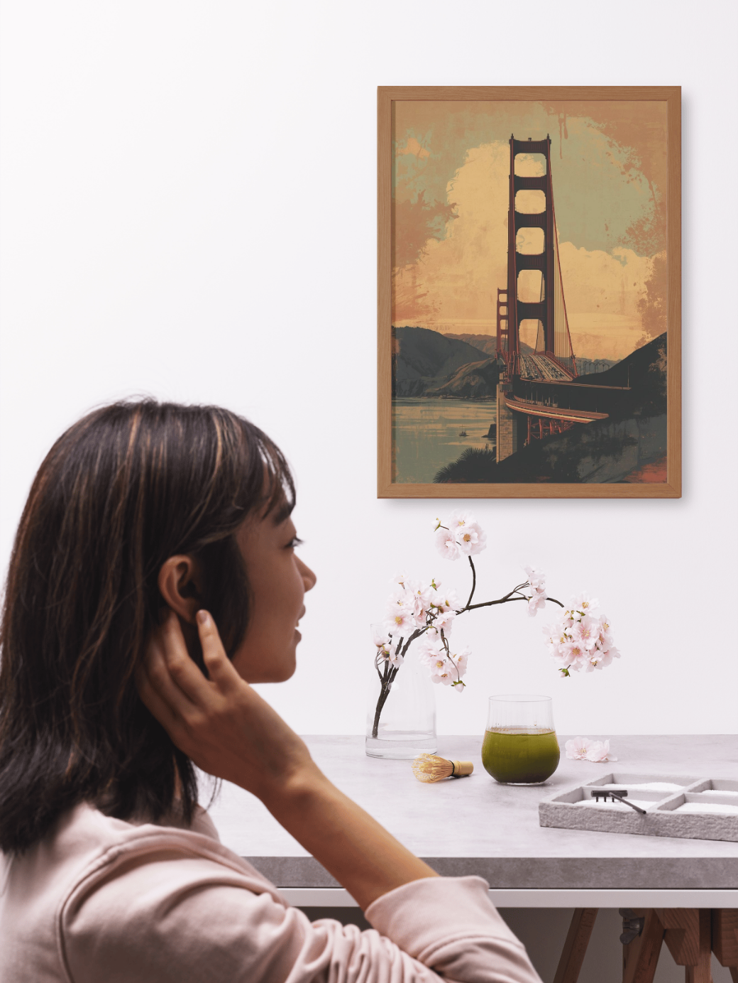 Woman sitting at a desk with a framed picture of the Golden Gate Bridge on the wall.