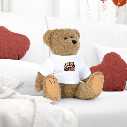 Brown teddy bear wearing a white shirt with a logo, sitting on a white surface with red heart-shaped objects in the background.