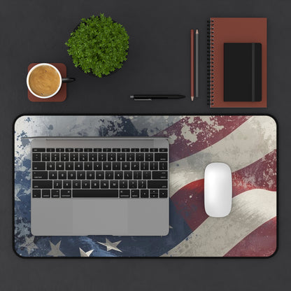 Laptop on a desk with an American flag design mouse pad desk mat, cup, plant, and office supplies.