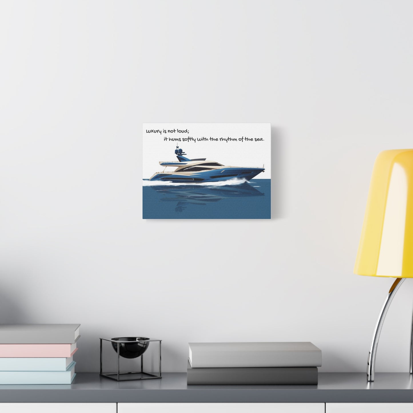 Canvas wall art of a yacht on water with text, displayed on a wall above a desk.
