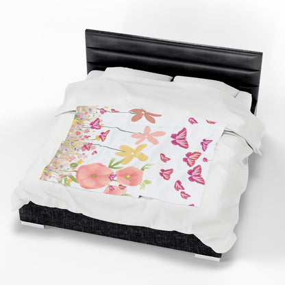 Floral and butterfly blanket on a bed with a black headboard.