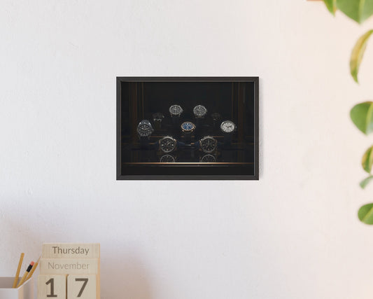 Framed artwork on a wall with a calendar and plant in the foreground