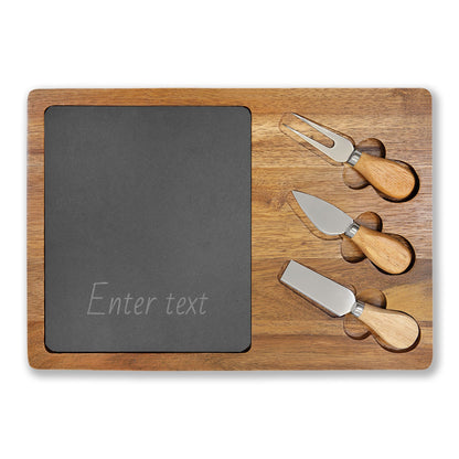 Wooden cutting board with slate surface and three cheese knives on a white background