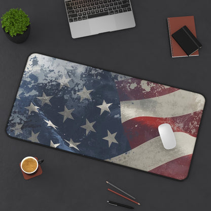 Desk setup with a large American flag mouse pad, laptop, phone, and office supplies on a dark surface.