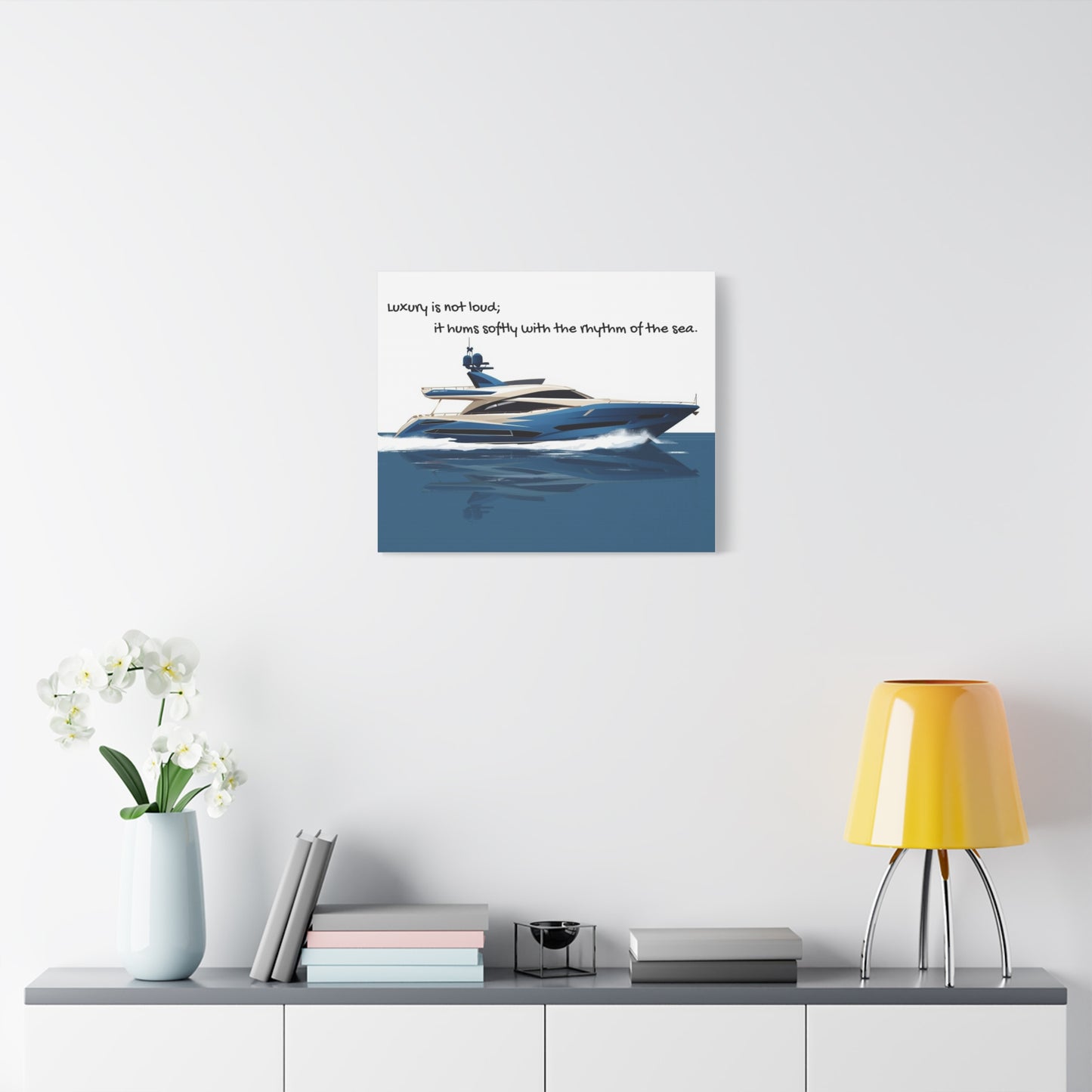 Canvas wall art of a yacht on a wall above a shelf with decor items.