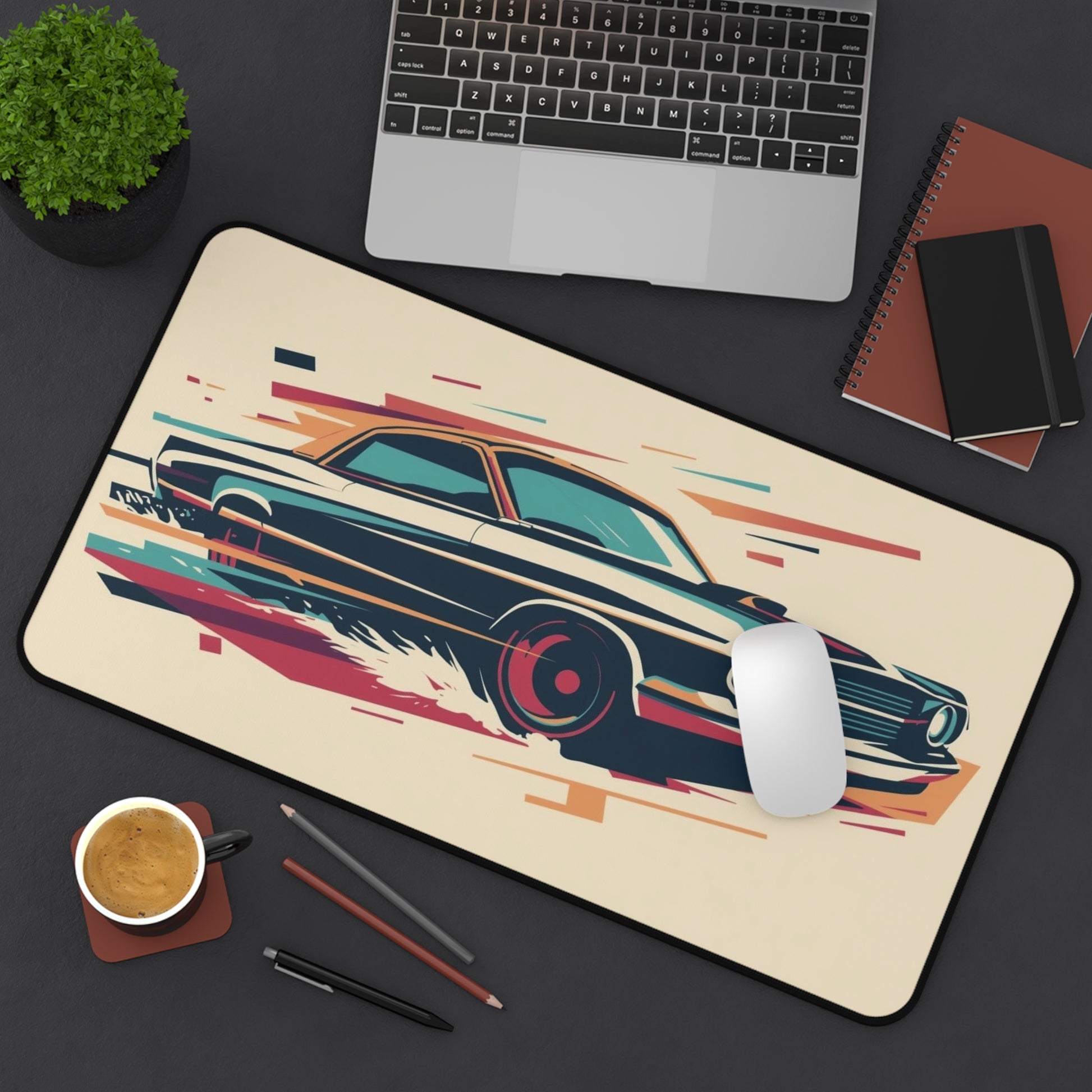 Desk setup with a mouse pad featuring a car design, laptop, notebook, and cup.